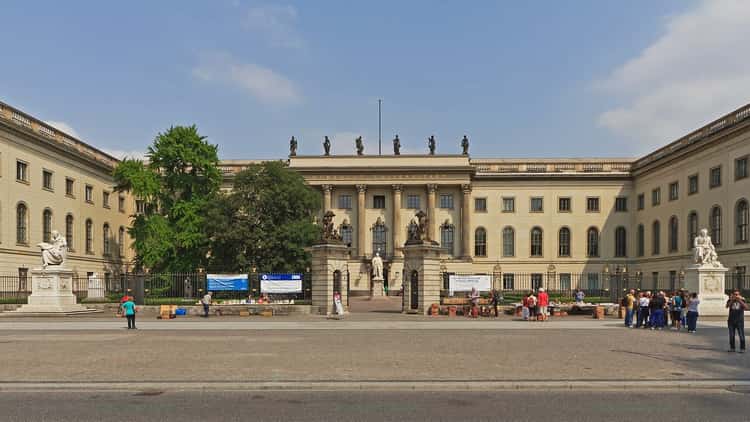 The main building of Humboldt University in Berlin, a long pale building behind a courtyard