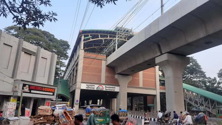 The Bangladesh Secretariat metro station in Dhaka, with rickshaws and traffic below the elevated line