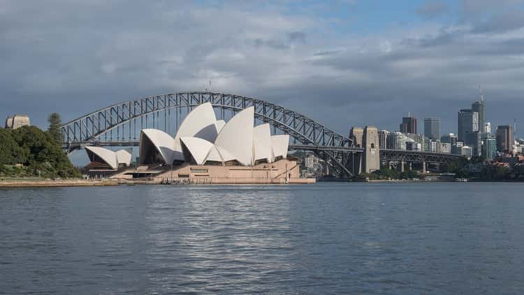 Sydney Opera House and the Harbour Bridge across the water on a cloudy day